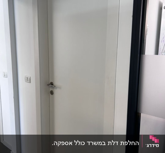 דלת לבנה עם ידית כסופה במסגרת לבנה